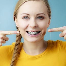 Woman pointing to her smile with braces