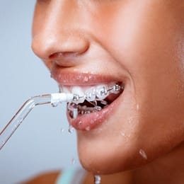 A person using a water pik to clean their teeth