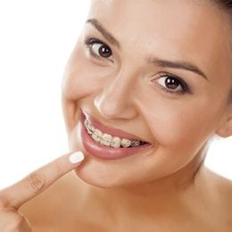 Woman in braces pointing at her smile 