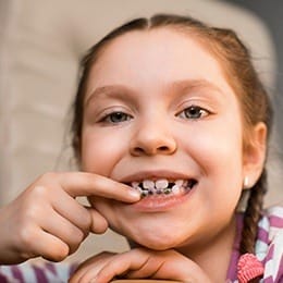 Little girl pointing to her orthodontic appliance