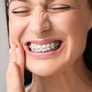 A woman rubbing her cheek during an emergency orthodontic visit