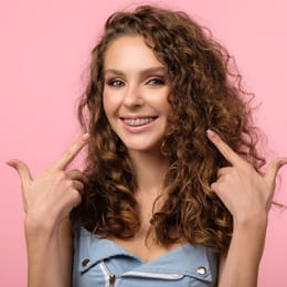 A young woman pointing to her smile