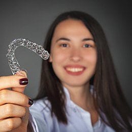 Young woman holding up Invisalign tray