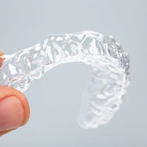 A person holding an Invisalign tray.