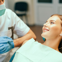 Patient with braces smiling at orthodontist in treatment chair