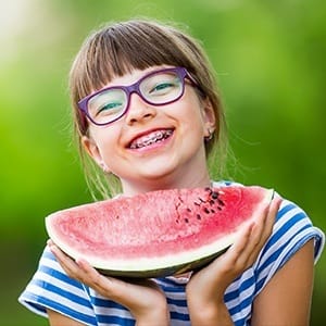 Young girl with braces holding a watermelon