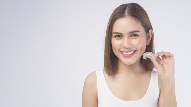 Woman smiling and holding a retainer