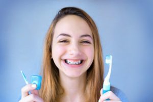 girl with braces holding toothbrush and other braces products 