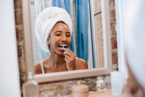 Woman looking in mirror and flossing her teeth