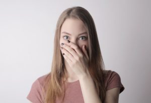 Young woman covering her mouth with hand